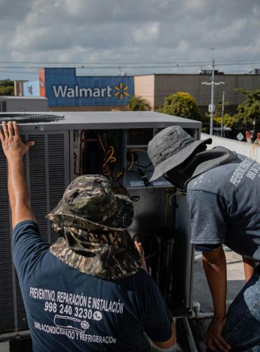 pexels-photo-5463577-5463577 Two technicians repair a rooftop HVAC unit outside a Walmart store.